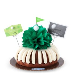 A golf themed bundt cake with a green bow in the center to represent the green grass with a small golf ball. A card reads hole in one.