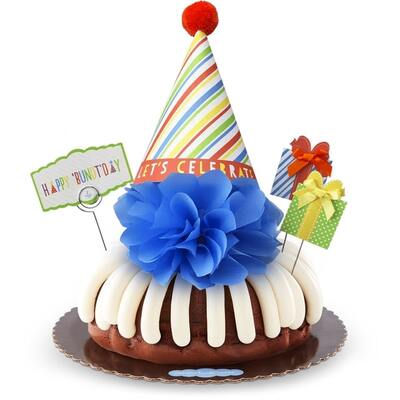 Bundt Cake with signature frosting decorated with paper bow, celebration hat and pom pom.