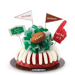 A Red Velvet bundt cake, decorated with a mini football on top of a green and white bow in the center of the cake.