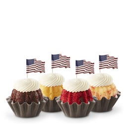 Mini Bundt cakes (Bundtinis&reg;) in a row with creamy white frosting. Each Bundtini is topped with a small American flag.